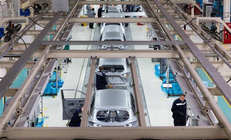 Varios carros siendo modificados en una fábrica de vehículos.