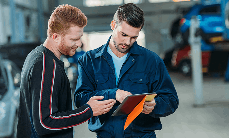 2 hombres revisando una tableta en un taller de carros eléctricos 